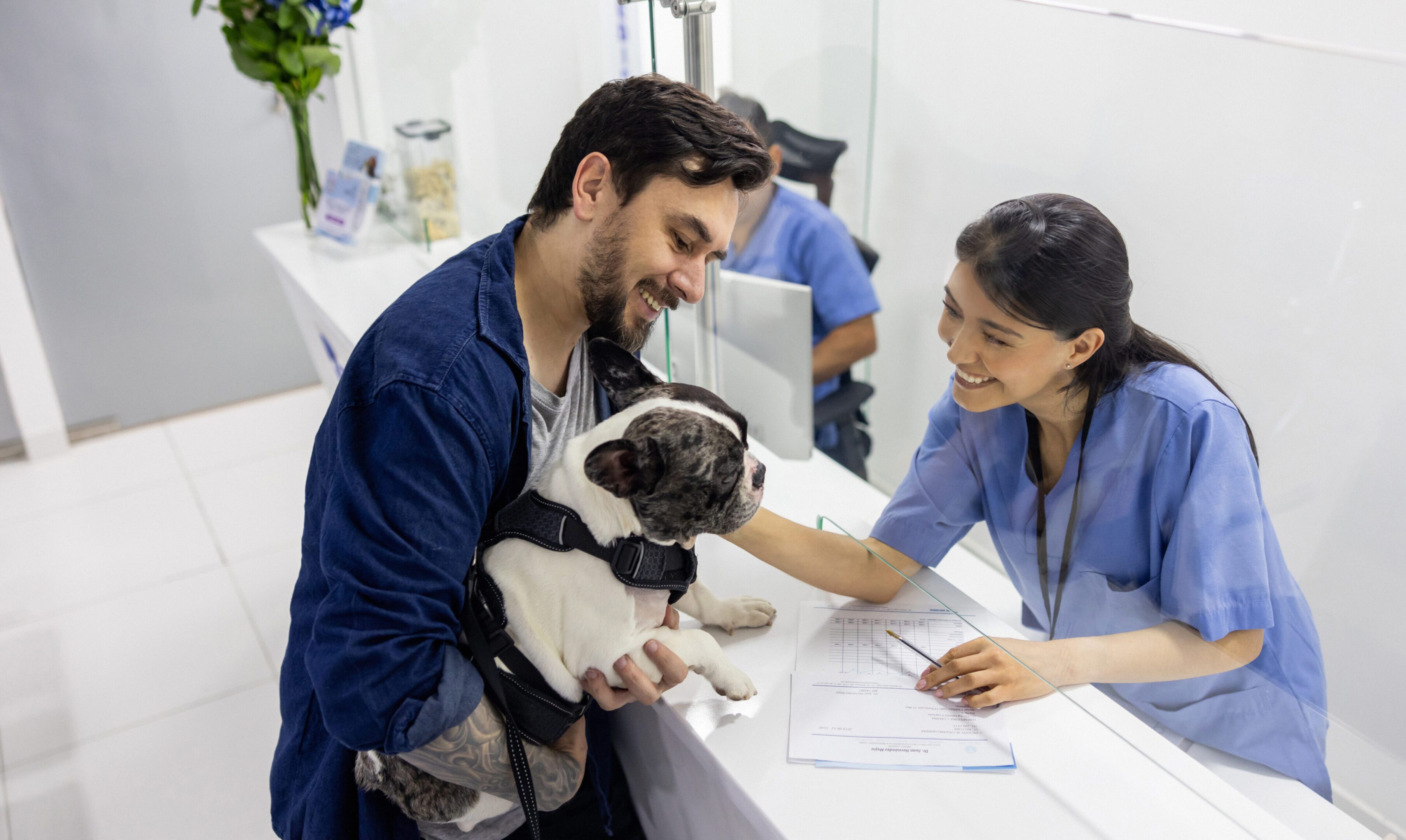 Smiling vet receptionist with client and dog