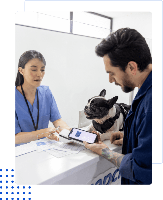 Vet and pet owner consulting at a clinic desk with a French bulldog.