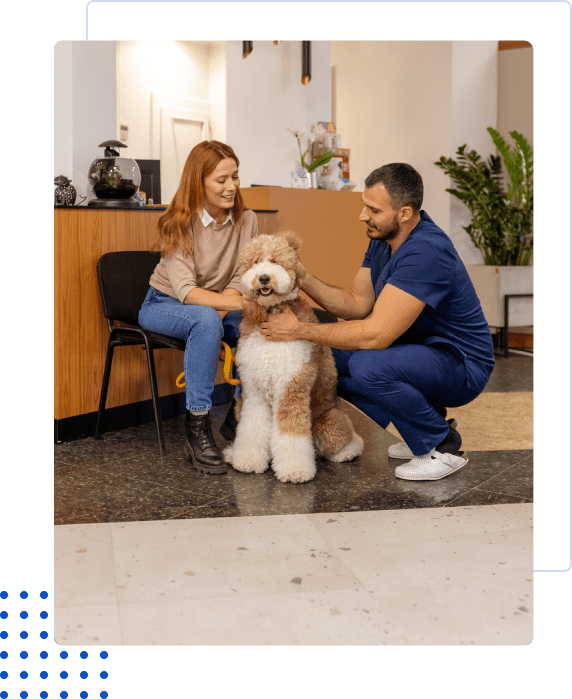 A woman and a man pet a large fluffy dog indoors.